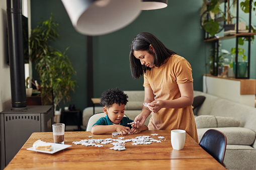 Shot of an adorable little boy completing a puzzle with his mother at home