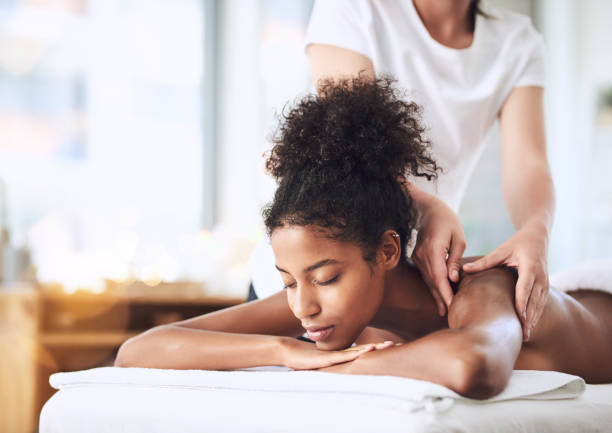 We will massage away all your tension Shot of a young woman getting a massage at a spa massage therapist stock pictures, royalty-free photos & images