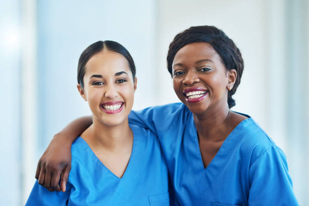 We work so well alongside each other Portrait of two female nurses standing in a hospital arm around stock pictures, royalty-free photos & images