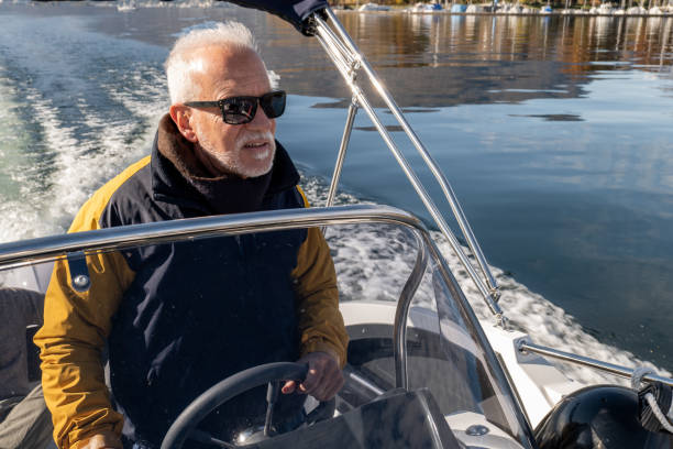 Wealthy mature man piloting boat on lake in Autumn stock photo