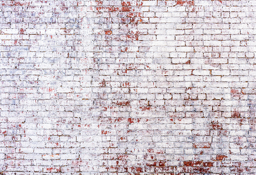 An old, distressed brick wall, with fading painted white wash.