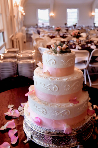 Photo of a wedding cake sitting in an empty reception hall.