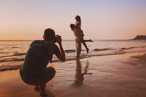 wedding portrait photographer taking photos of honeymoon couple on the beach at sunset, professional photography