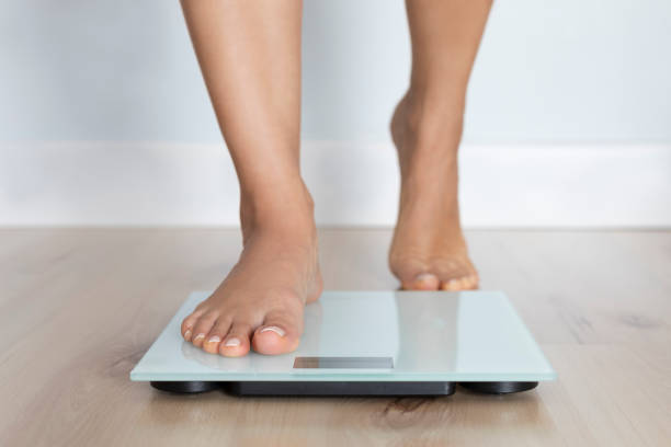 Weighing Scale Barefoot female is about to get on weighing scale. feet unit of measurement stock pictures, royalty-free photos & images