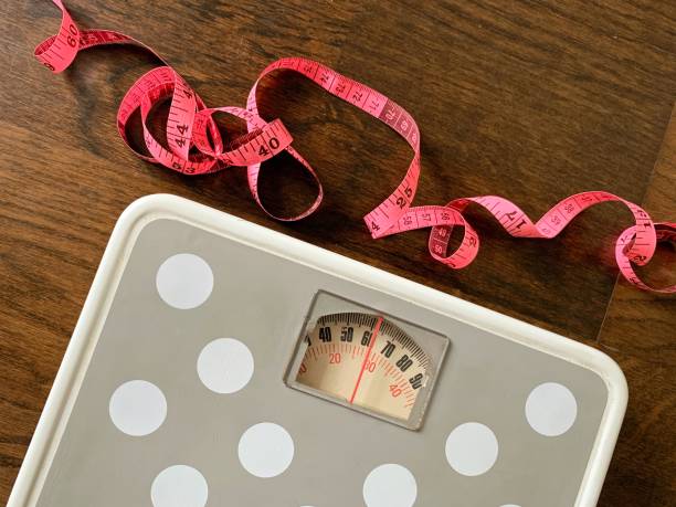 Weight scale and measuring soft tape close up image. Fitness and weight loss concept Weight scale and measuring soft tape close up image. Weight loss concept obesity stock pictures, royalty-free photos & images