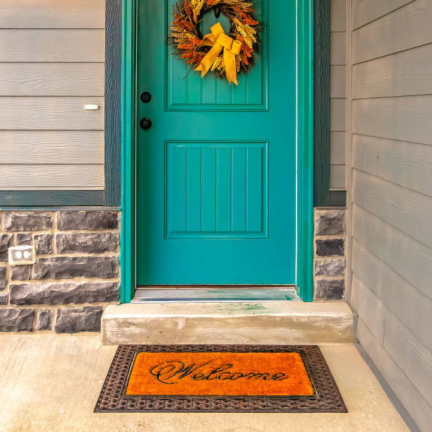 Welcome doormat in front of a door with wreath stock photo