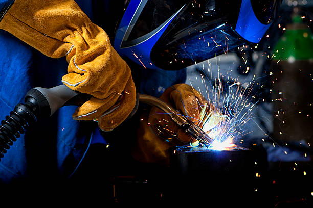 Welder with welding sparks Welder wearing gloves and mask with welding sparks. metalwork stock pictures, royalty-free photos & images