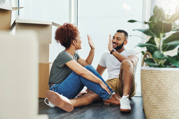 Well done on securing a new castle for us! Shot of a young couple giving each other a high five while moving house unpacking stock pictures, royalty-free photos & images