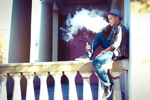 Well dressed man smoking sitting on a street sidewalk stock photo