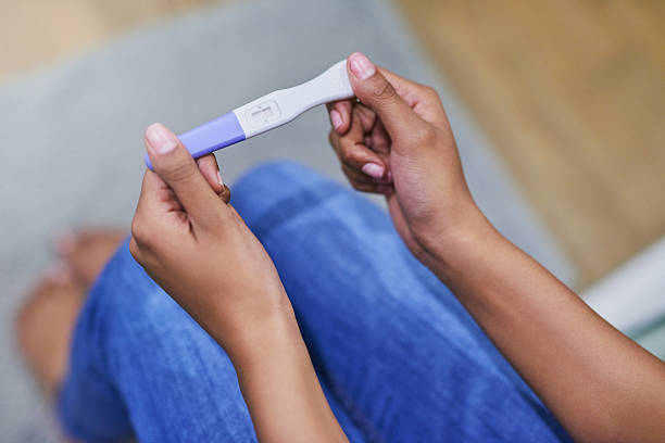 Well, this is a surprise Shot of an unidentifiable woman holding a pregnancy test while sitting in her bathroom positive pregnancy test stock pictures, royalty-free photos & images