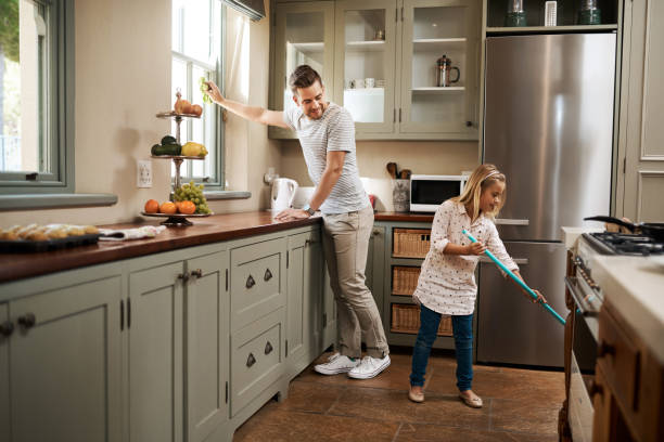 We're giving mom the day off Shot of a young man and his daughter cleaning the kitchen at home chores photos stock pictures, royalty-free photos & images