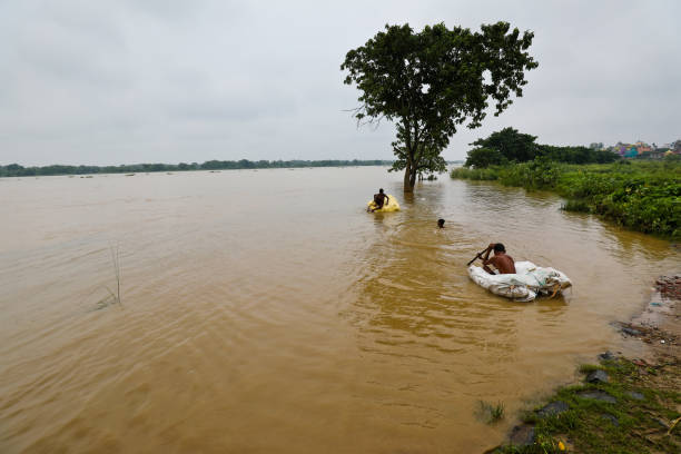 2021 West Bengal Flood - countryside flooded and natives crossing flooded river on makeshift raft stock photo