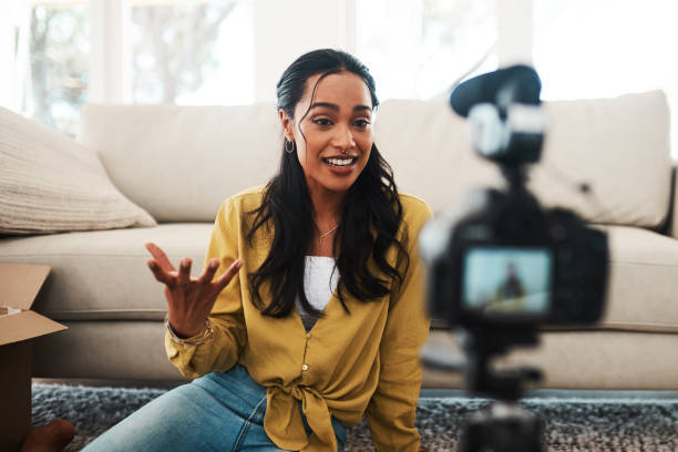 What do you guys think of this? Cropped shot of an attractive young businesswoman sitting in her living room and using her camera to record her vlog vlogging stock pictures, royalty-free photos & images