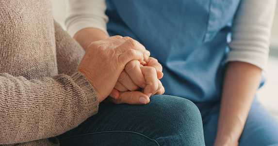 Cropped shot of a nurse and senior woman holding hands