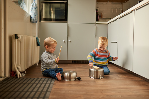 Shot of two adorable young brothers banging on pots and pans in the kitchen at home