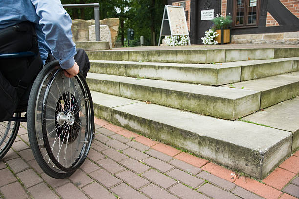 Wheelchair user in front of staircase barrier (XXL) stock photo