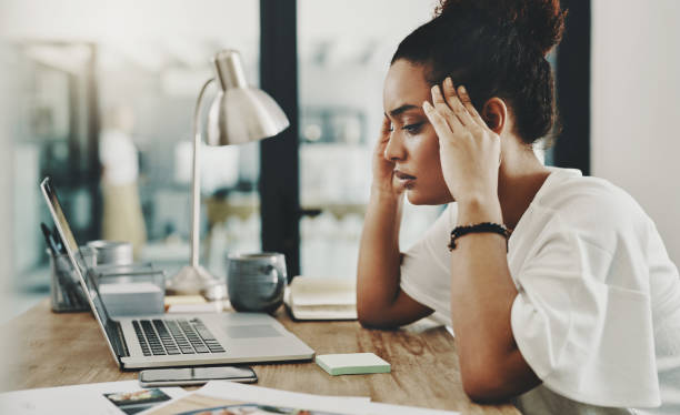When hard work results in a headache Shot of a young businesswoman looking stressed while using a laptop in her home office disappointment stock pictures, royalty-free photos & images