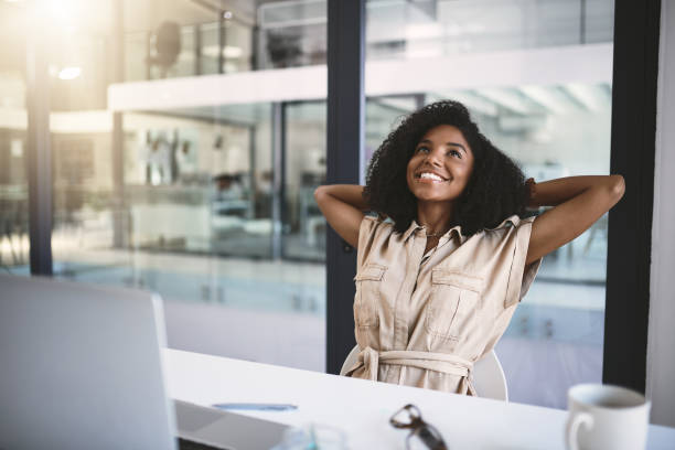 When work feels like a vacation Shot of a happy young businesswoman relaxing at her desk in a modern office happy friday stock pictures, royalty-free photos & images
