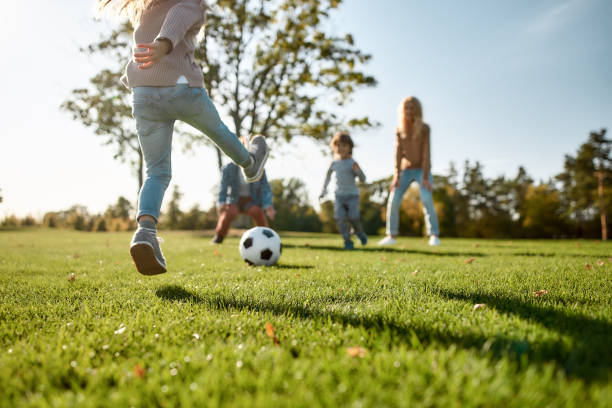 家庭樂趣從何而來。快樂的家庭在草地上玩球 - 公園 人造空間 個照片及圖片檔
