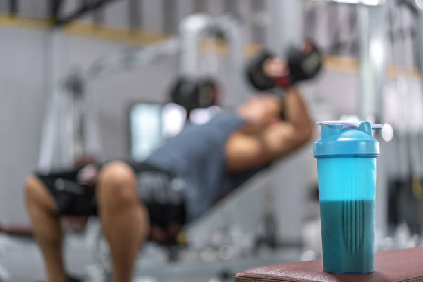 Whey protein at gym with Young Asian man working out his chest muscle  in the background stock photo