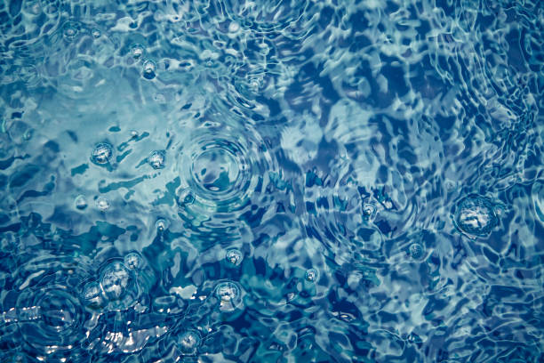 Whirling water background with bubbles and ripples in swimming pool in blue toned colors stock photo