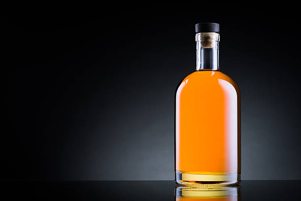 Whiskey bottle on black glass surface stock photo