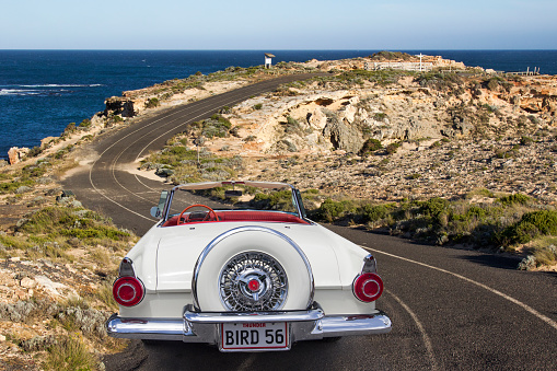 Port MacDonnell, South Australia - July 22, 2017: Rear view of a 1956 Ford Thunderbird convertible parked on the side of a winding coastal road. Limestone coast, Great Australian Bight.