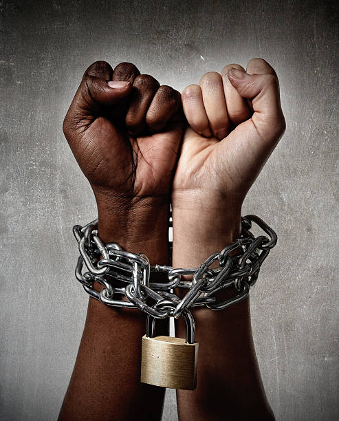White and Afro-American hands locked together by a chain stock photo