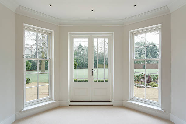 white bay windows and French doors a beautifully crafted set of Georgian style white wooden bay windows with French doors. These are from an expensive new mansion house. The views are towards a frost garden outside. Three spot lights are mounted in the ceiling above. window frame stock pictures, royalty-free photos & images