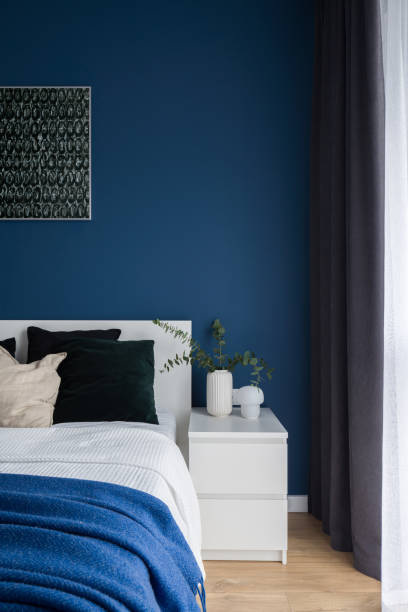 White bedside table in bedroom with blue wall stock photo