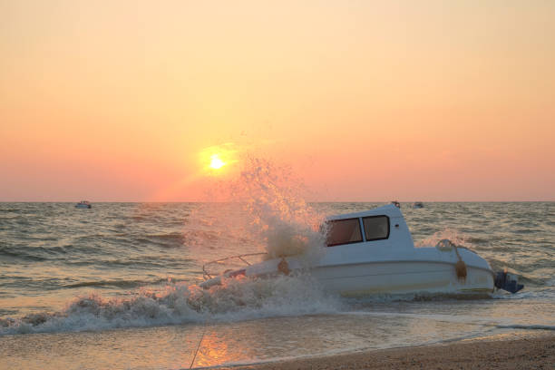 white boat drowned in the waves of the sea stands on the shore white boat drowned in the waves of the sea stands on the shore with big waves capsizing stock pictures, royalty-free photos & images