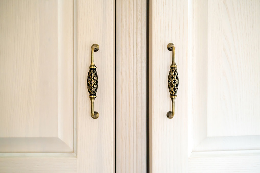 White wood cabinet doors with vintage fittings, retro Provence style door handles, interior details.