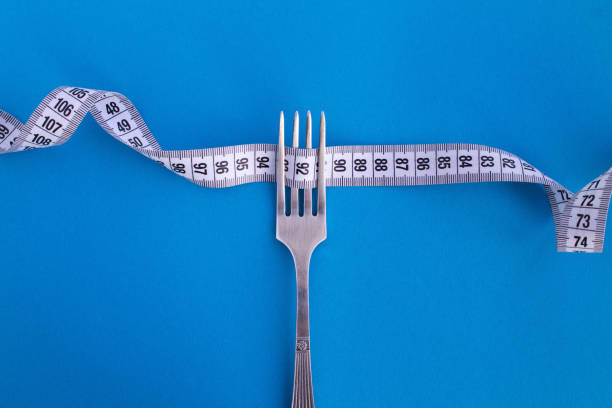 White centimeter and fork on the blue background. Top view. Copy space. stock photo