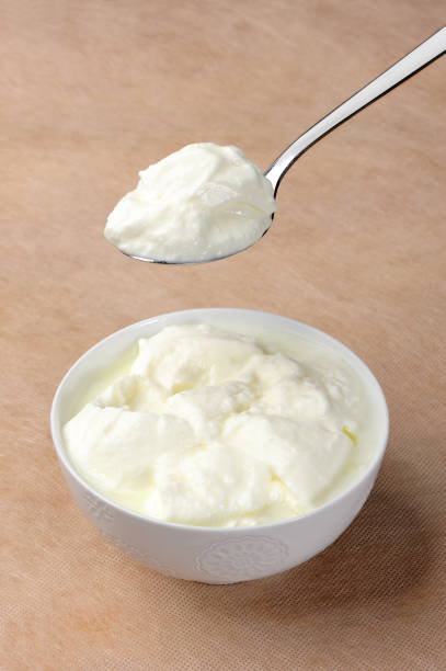 White ceramic bowl of yogurt on a wooden table stock photo