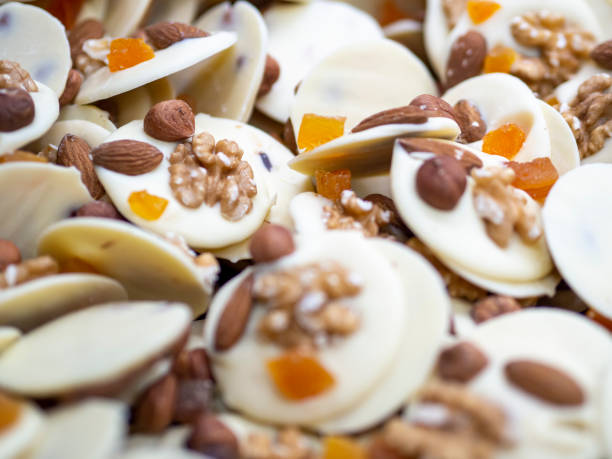 White chocolate confections with almond, walnuts and candied fruit on top. stock photo