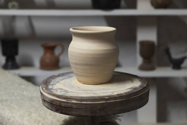 White clay pot stands on a pottery wheel, closeup stock photo