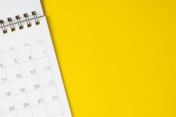 White clean calendar on solid yellow background with copy space, business, travel or project planning concept White clean calendar on solid yellow background with copy space, business meeting schedule, travel planning or project milestone and reminder concept. monthly event stock pictures, royalty-free photos & images