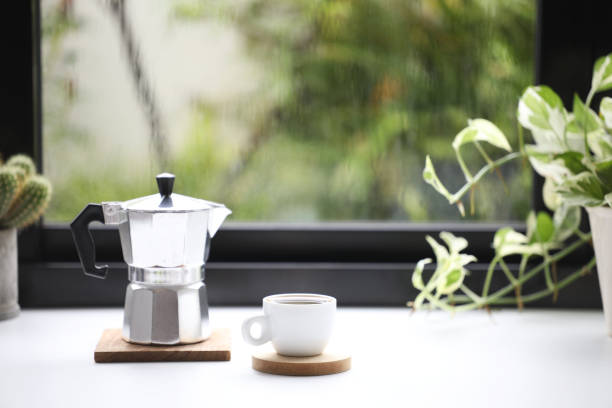 White coffee cup and stainless moka pot in front of window White coffee cup and stainless moka pot in front of window jade pothos stock pictures, royalty-free photos & images