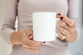istock White coffee mug mockup for design demonstration. Stylish cup mock up in female hand. 1346122116