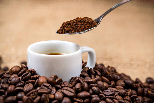 White coffeecup on coffeebeans with spoon above stock photo