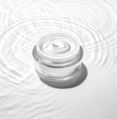 White cosmetic jar on the water surface. Summer water pool fresh concept.