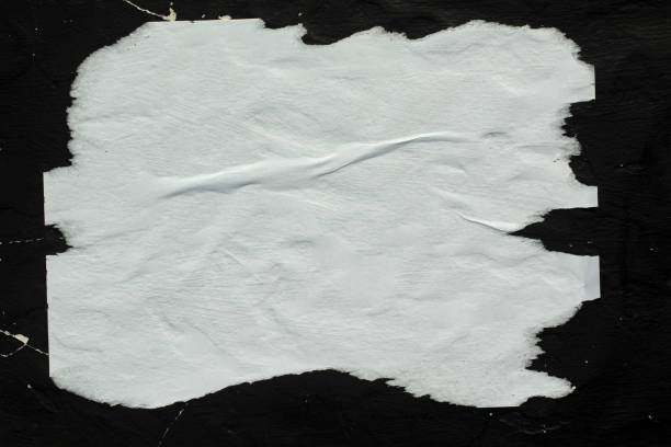 White crumpled paper pasted on a black wall. stock photo