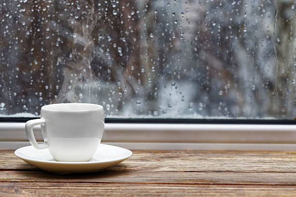 White cup on wooden windowsill White steaming cup of hot tea or coffee on vintage wooden windowsill or table against window with raindrops on blurred background. Shallow focus. window sill photos stock pictures, royalty-free photos & images