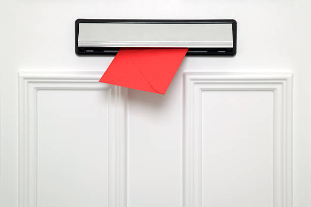 White door with a red envelope coming through the letterbox stock photo
