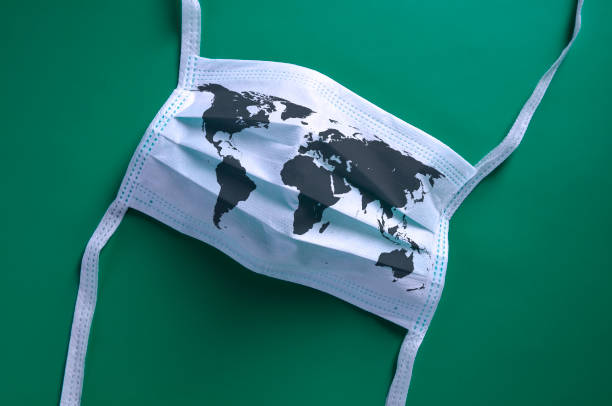 White face mask with a map of the world is lying on a blue background.