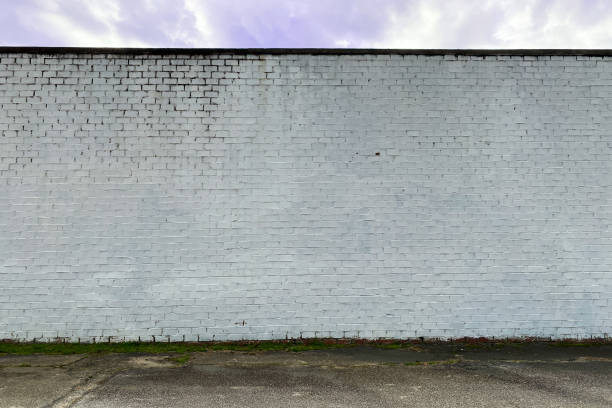 white faded stone brick factory warehouse wall alley stock photo