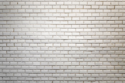 Full frame close-up on a white faience wall of the Paris Metro.