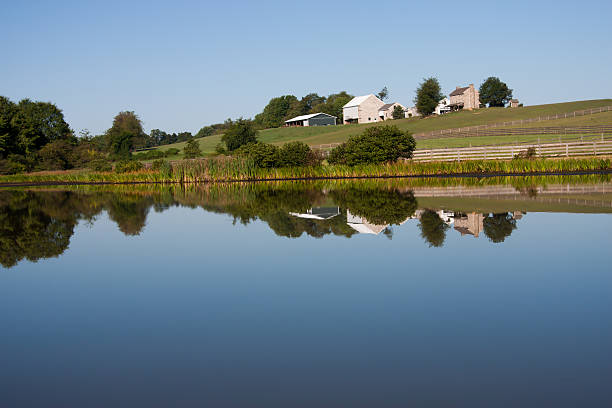 White farmhouse reflects in pond stock photo