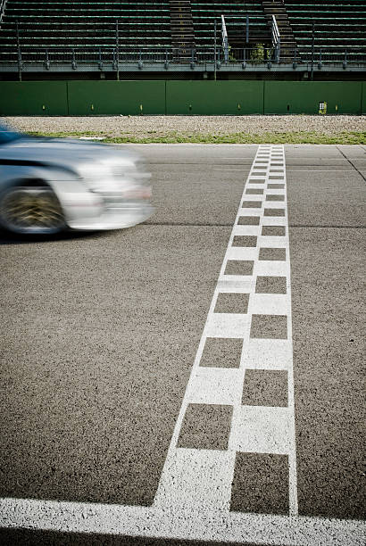 White finish line with car nearly crossing it on road stock photo
