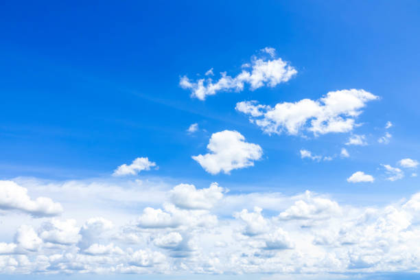 white fluffy light clouds in a bright blue sky stock photo